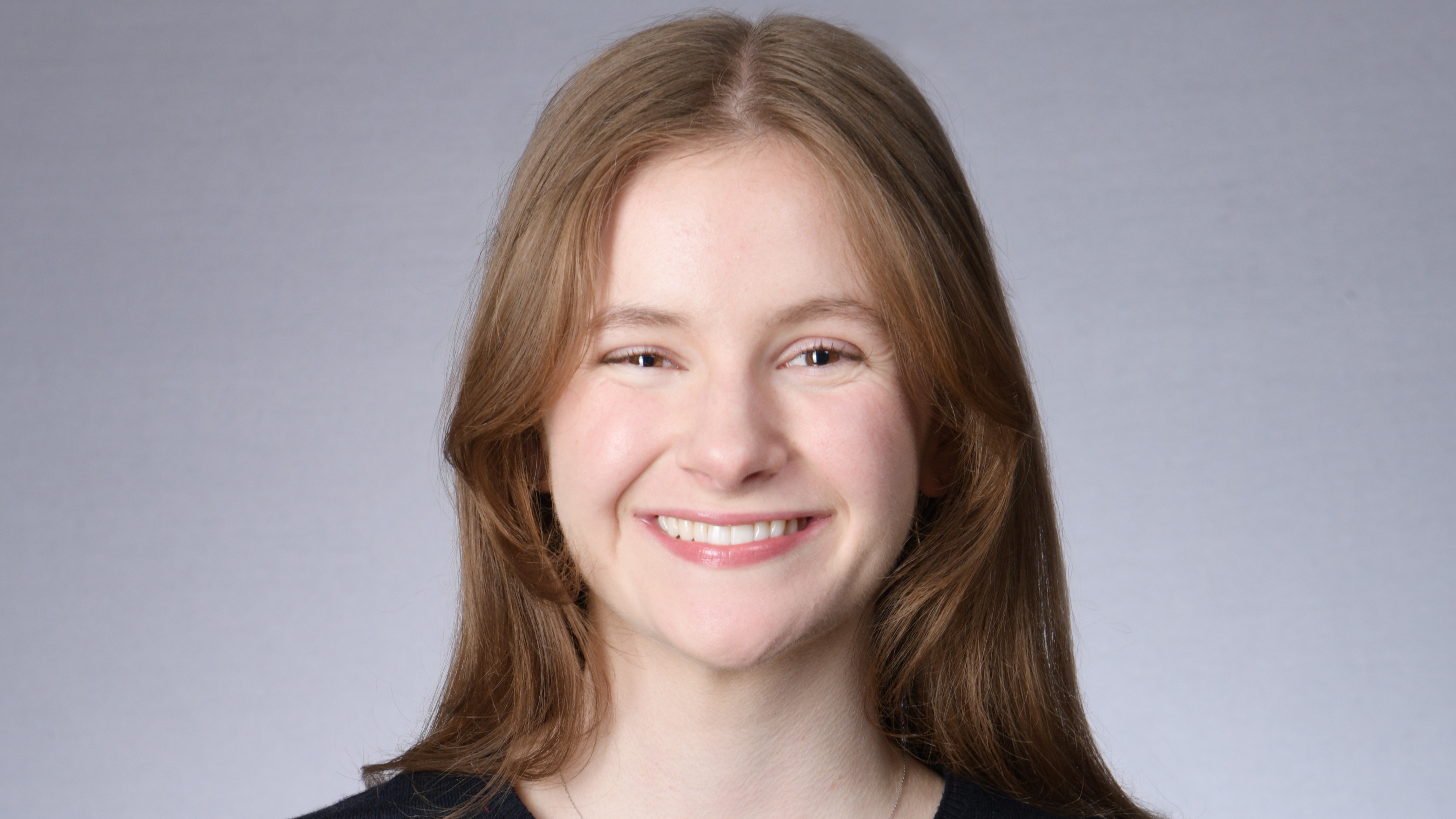 Charlotte Fithian smiles in front of a gray background wearing a black shirt. Charlotte Fithian smiles in front of a gray background wearing a black shirt.